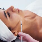 Woman that lying down in spa salon and have injection by the syringe into her face skin