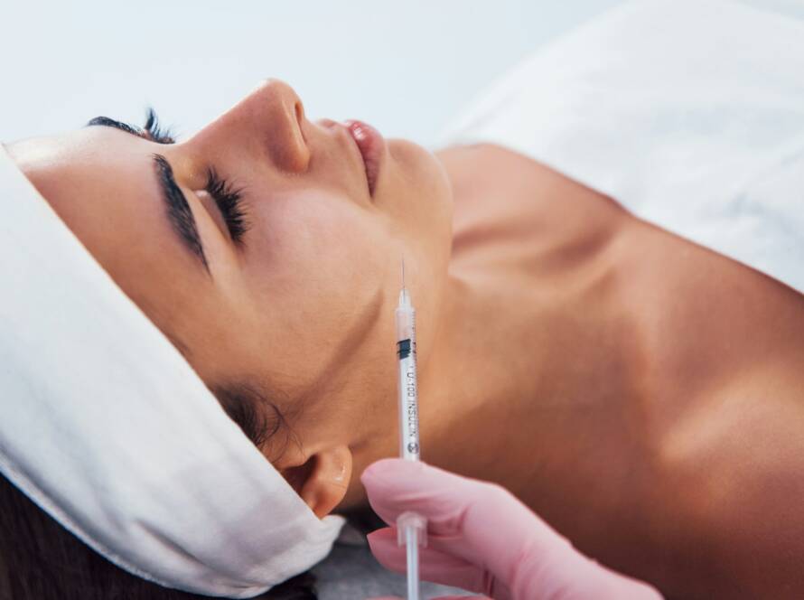 Woman that lying down in spa salon and have injection by the syringe into her face skin