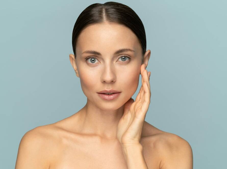 Woman with natural makeup, combed hair, touching well-groomed pure skin on face. Beauty, facelift
