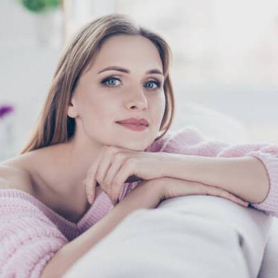 Close up portrait of calm relaxed charming beautiful gorgeous attractive in good mood pretty woman resting in house leaning on the back of divan wearing knitted warm jumper