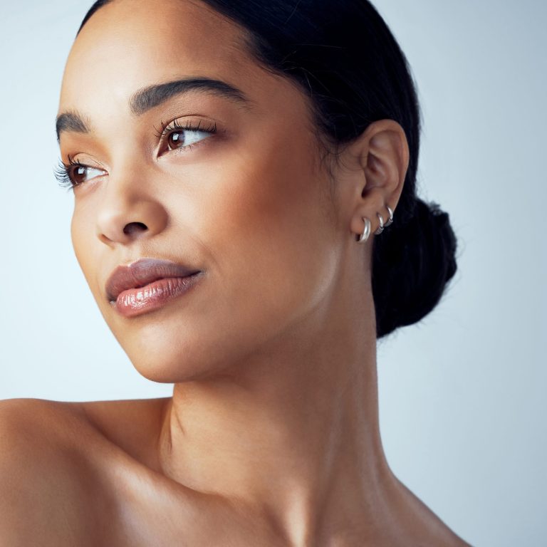 Studio shot of an attractive young woman posing against a grey background.