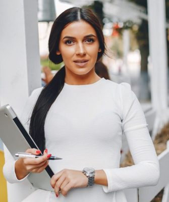 Beautiful girl with a laptop. Woman in a summer city. Lady in a white blouse