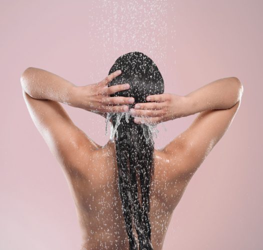 Woman, hair and back in studio with water, pink background and relaxing for cleaning or model washing. Grooming, hygiene and female person or wet for self care, showering and wellness routine.
